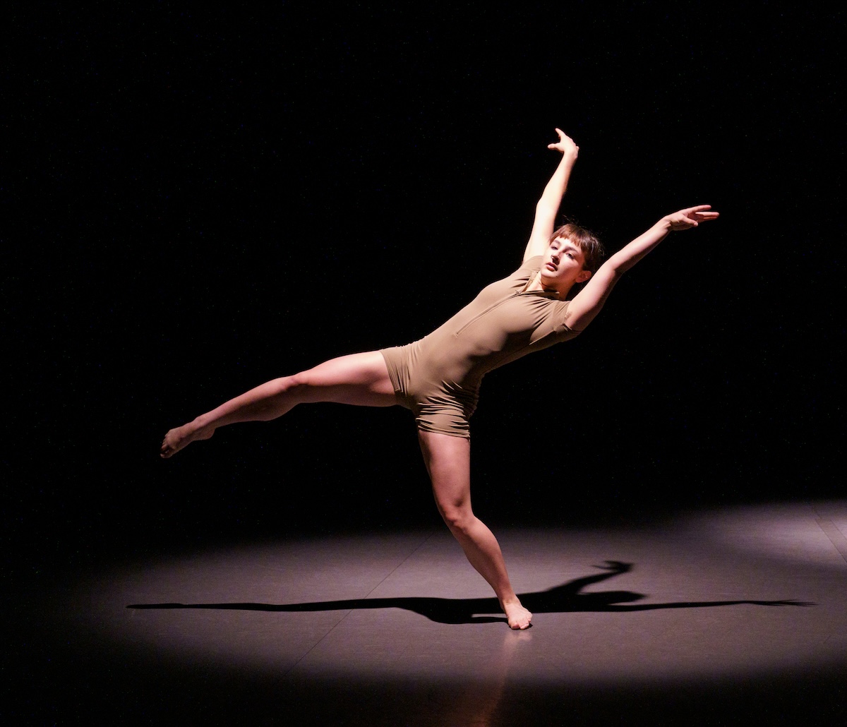 dancer arching back on one leg with arms outstretched